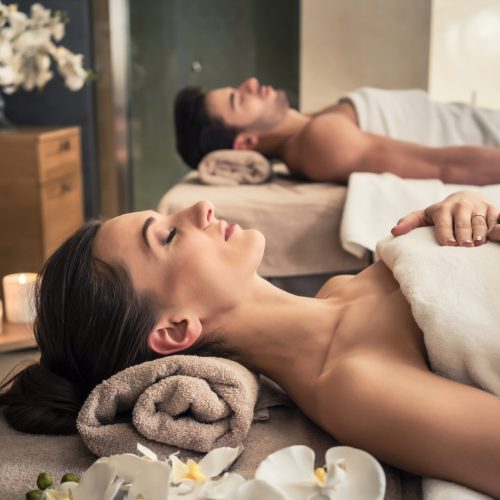 Young man and woman lying down on massage beds at Asian luxury spa and wellness center