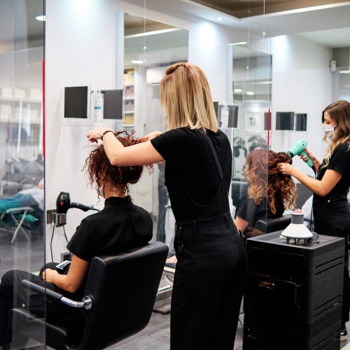 women in a beauty salon with social distance and protective masks - new normal