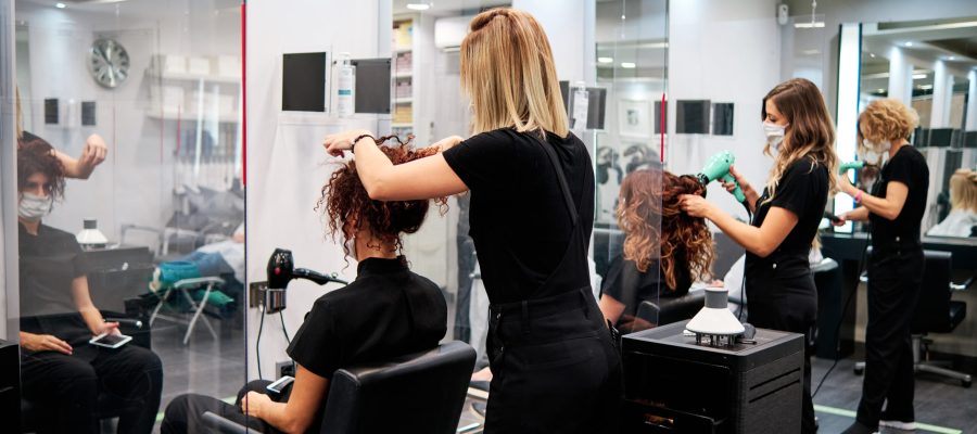 women in a beauty salon with social distance and protective masks - new normal